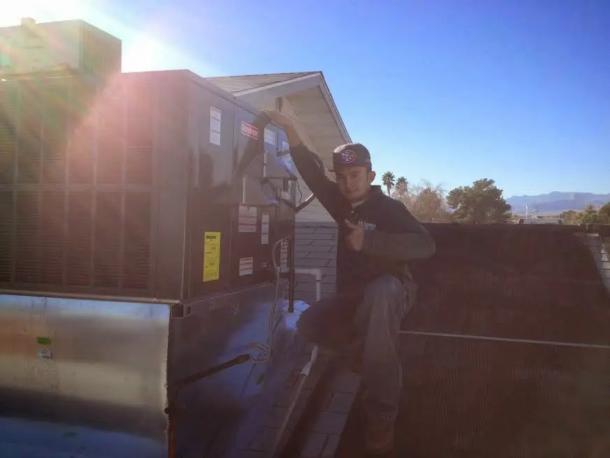 HVAC technician performing Air Duct Repair on a rooftop unit in Fayetteville